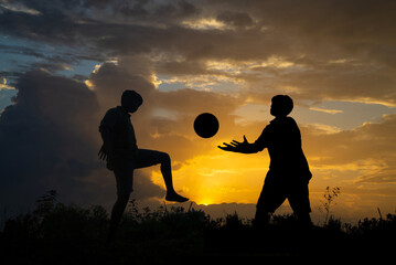 Silhouette of boy playing football during sky sunset background, Silhouette Boy Standing On Field Against blue cloudy Sky