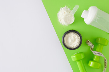 Sports nutrition concept. Top view photo of whey protein in jar with scoop, shaker and dumbbells on...