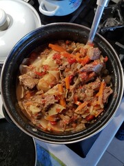 Potatoes and meat with vegetables in tomato sauce on a white plate