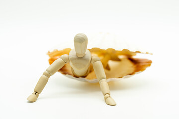 Maniquí de madera articulado saliendo de una ostra, con fondo blanco