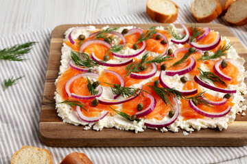 Homemade Cream Cheese Lox Bagel Board with Salmon on a white wooden background, side view.