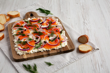 Homemade Cream Cheese Lox Bagel Board with Salmon on a white wooden background, low angle view....