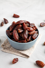 Pitted Organic Dates in Bowl on gray background, low angle view.