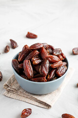 Pitted Organic Dates in Bowl on gray background, side view. Copy space.
