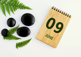 June 09. 09th day of the month, calendar date. Notepad, black SPA stoneJune s, green leaves. Summer month, day of the year concep