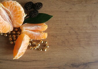 Mandarin slices on a wooden table with a green leaf and gold beads