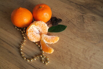 Mandarin slices on a wooden table with a green leaf and gold beads