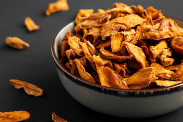 Delicious Organic Dried Mango Fruit in a Bowl on a black background, side view.