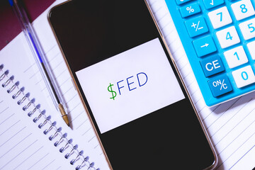 The initials FED on a smartphone screen. A calculator, a notebook and a pen in the composition of...