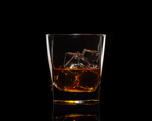 whiskey with ice in a transparent glass on a black background with highlights