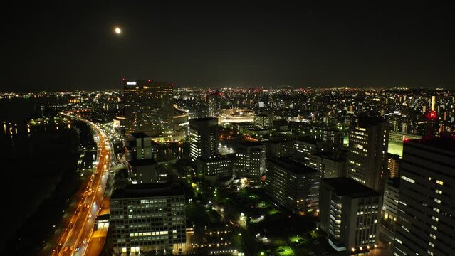 FUKUOKA, JAPAN - NOV 2022 : Aerial high angle view of Fukuoka City and full moon at night. View around Tenjin and Nakasu downtown area. Travel and urban city nightlife concept video.