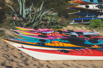View of colorful kayaking equipment on a sandy beach, process of kayaking by the Ionian sea beach,...