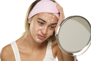 Unhappy sad woman posing with face cream on a white background