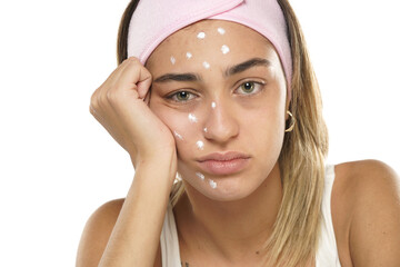 Unhappy sad woman posing with face cream on a white background