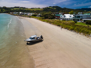 Amphibious fishing boat with Sea Legs driving from beach out to sea along New Zealand coastal town...