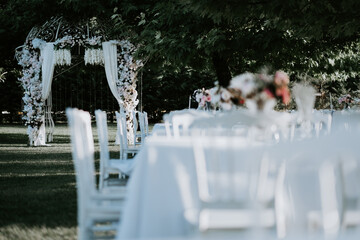 White chairs arranged in the garden during the wedding festively decorated tables outdoors