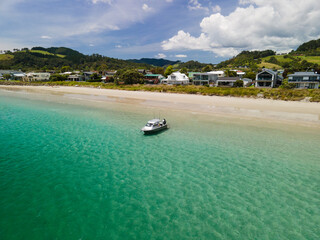 Amphibious fishing boat with Sea Legs driving from beach out to sea along New Zealand coastal town in the Coromandel Peninsula