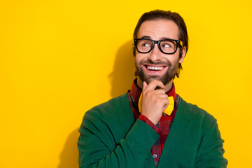 Photo portrait of young nice guy spectacles touch chin look empty space wear trendy green garment isolated on yellow color background