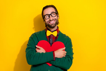 Obraz premium Photo of cheerful guy arms hold embrace paper heart card look empty space isolated on yellow color background