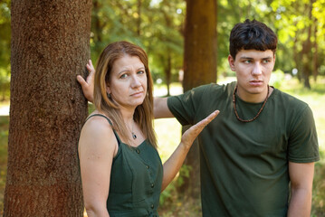 A woman and her teenage son are talking alone in the park, the mother points to her son because he is angry with her and the woman no longer knows how to raise him