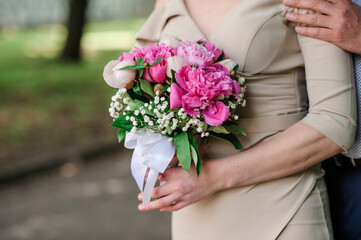 Obraz na płótnie Canvas A bouquet of flowers in the hands of the bride. A bouquet of flowers with pink peonies in the hands of a woman. Wedding