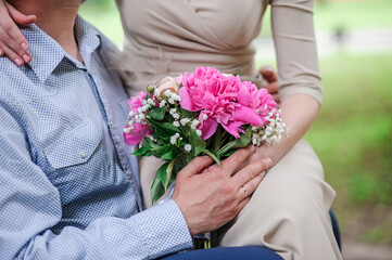 A bouquet of flowers in the hands of the bride. A bouquet of flowers with pink peonies in the hands of a woman. Wedding