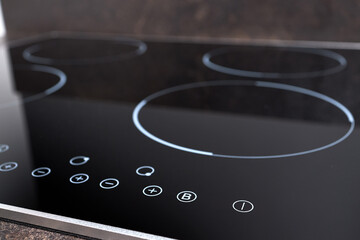 Modern induction electric hob cooker with control panel buttons. Electric hob detail closeup. Stove top panel controls of modern kitchen. Electric hob ceramic surface and touch control panel.