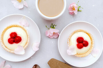 Delicious red raspberry strawberry whipped creamy tartlets,cakes.gourmet confection dessert on plate with latte coffee,milk.sweet tasty pastry baked pie cheesecake with ripe berries on gray table