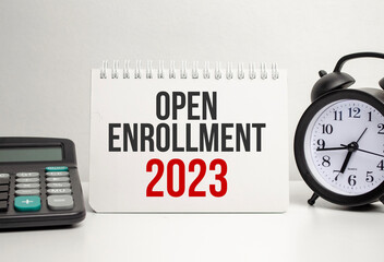 OPEN ENROLLMENT 2023 words with calculator and clock with notebook