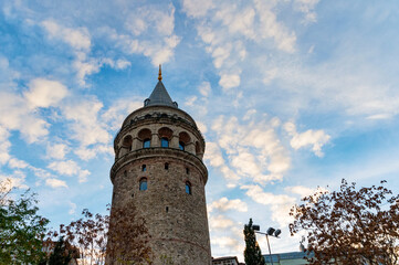 View of Galata Tower from below surrounded by classic buildings against blue sky