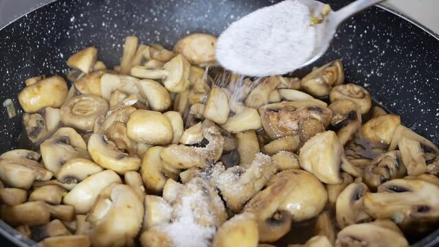 Adding a tablespoon of sugar when frying mushrooms, champignons. Selective focus, close-up