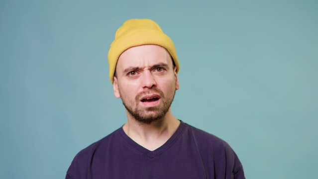 guy demonstrating disbelief irritation by troubles Indignant bearded guy in yellow cap looking with disgruntled confused annoyed expression asking what why How could you. studio shot blue background