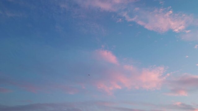 The plane took off from the airport and flies high in the sky during sunset with pink clouds. The beginning of a vacation, a flight into the sunset. High quality 4k footage