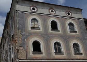 Facade of an old historic brick building with beautiful paintings. Uninhabited building, probably intended for renovation