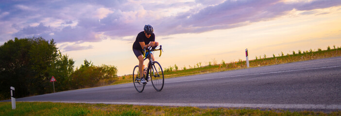 Young sports man cycling with bicycle on the road in summer	