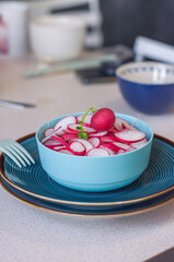 Radishes cut into rings lie in a blue plate for a snack