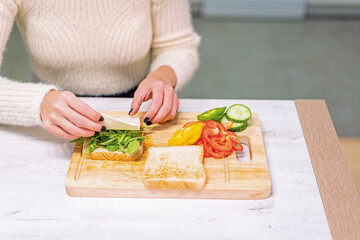 Unrecognizable person cooking a vegetable sandwich in the kitchen at home. placing the cheese