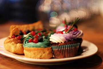cakes on a plate - cupcakes and eclairs, close up