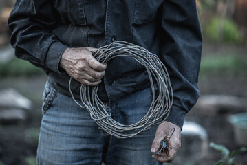 the worker is holding a roll of metal wire in his hand