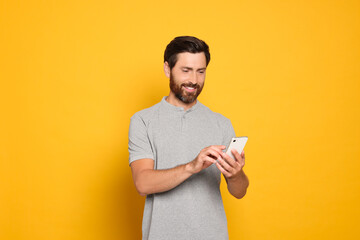 Happy man with smartphone on yellow background