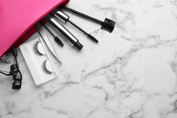 Flat lay composition with false eyelashes and tools on white marble table. Space for text