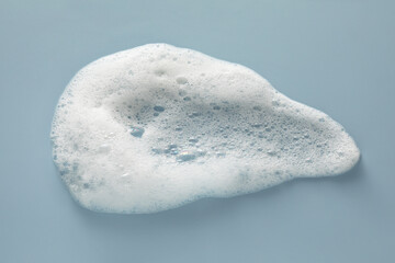 Smudge of white washing foam on color background, top view