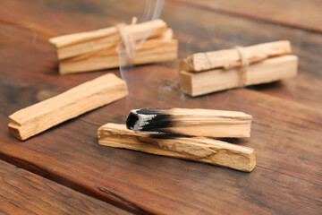 Palo Santo stick smoldering on wooden table, closeup