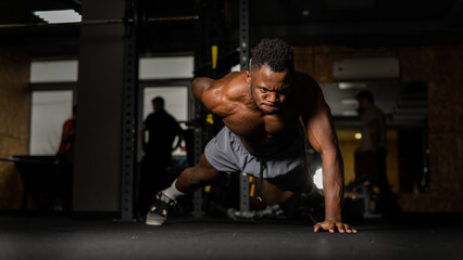 Naklejka na ściany i meble African american man doing one arm push ups in the gym. 