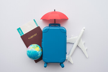 Red umbrella cover airplane, passport, globe, flight tickets and suitcases travelers on white...