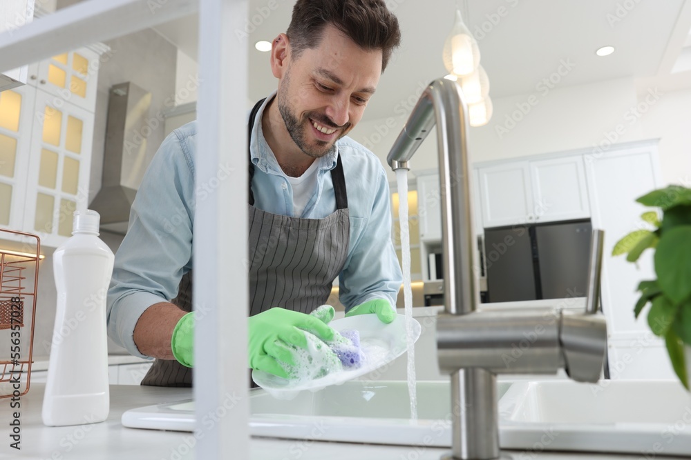 Wall mural Man washing plate above sink in kitchen