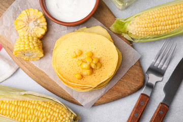 Tasty corn pancakes with sweet kernels and sauce served on light grey table, flat lay
