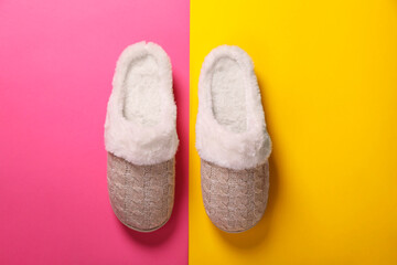 Pair of beautiful soft slippers on colorful background, top view