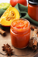 Jar of delicious pumpkin jam and ingredients on tiled surface, closeup