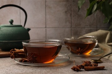Aromatic tea with anise stars and cinnamon sticks on light grey table. Space for text